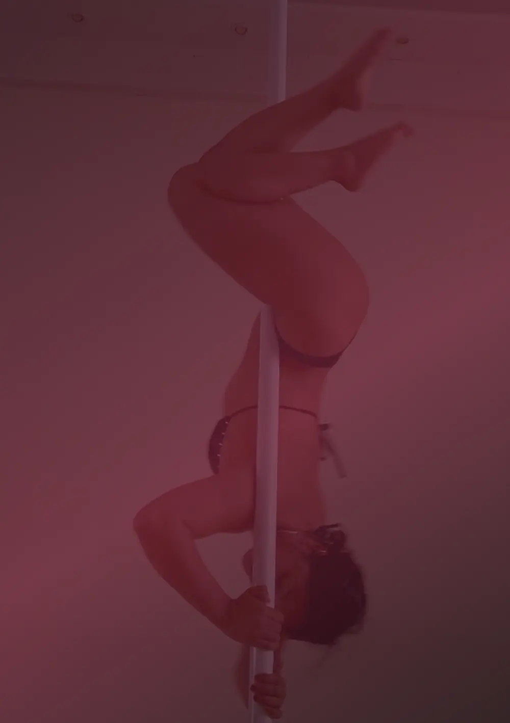 Pole danseuse en inversion sur la barre, lumière rouge